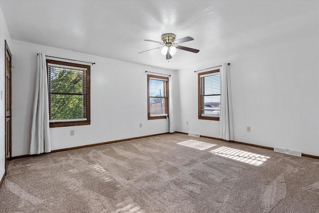 spare room with a wealth of natural light, ceiling fan, and carpet flooring