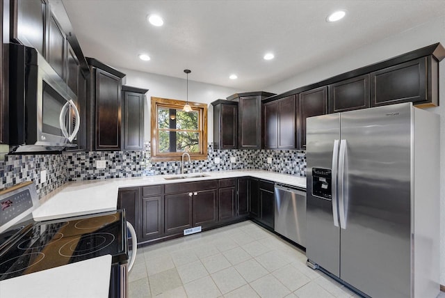 kitchen featuring stainless steel appliances, dark brown cabinetry, hanging light fixtures, sink, and backsplash