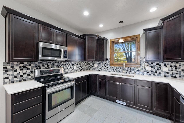 kitchen with stainless steel appliances, decorative backsplash, dark brown cabinetry, sink, and decorative light fixtures