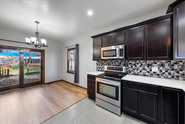 kitchen featuring tasteful backsplash, stainless steel appliances, light wood-type flooring, dark brown cabinetry, and an inviting chandelier