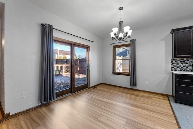 unfurnished dining area with light hardwood / wood-style floors and a chandelier