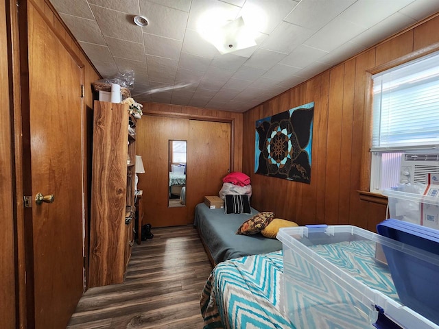 bedroom featuring cooling unit, wooden walls, and dark hardwood / wood-style floors