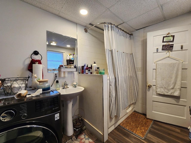 bathroom with shower / bathtub combination with curtain, a paneled ceiling, hardwood / wood-style floors, and washer / dryer