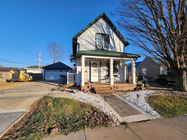 view of front of house featuring a garage, central air condition unit, covered porch, and an outbuilding