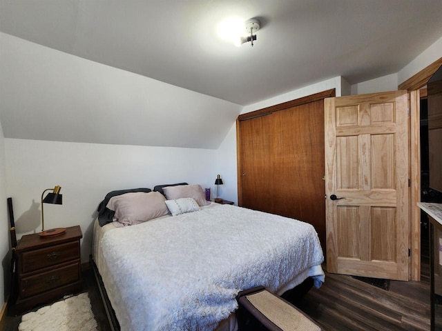 bedroom featuring dark hardwood / wood-style floors, vaulted ceiling, and a closet