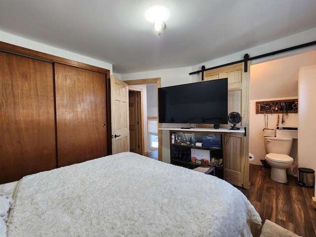 bedroom with a closet, dark hardwood / wood-style flooring, and connected bathroom