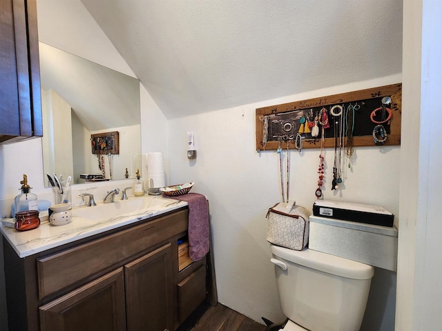 bathroom with toilet, hardwood / wood-style floors, vanity, and vaulted ceiling