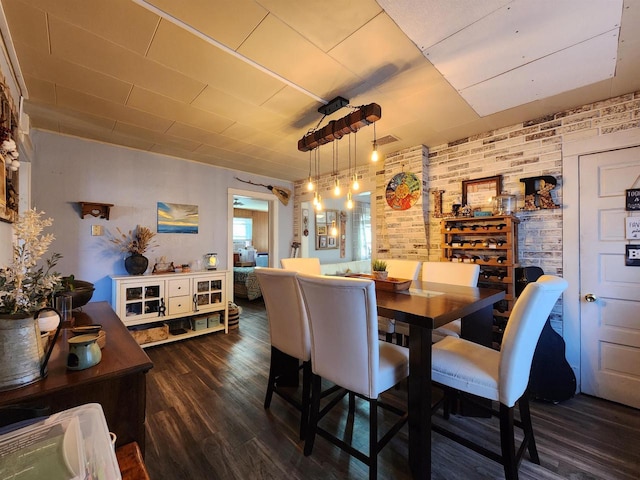 dining room featuring brick wall and dark hardwood / wood-style floors