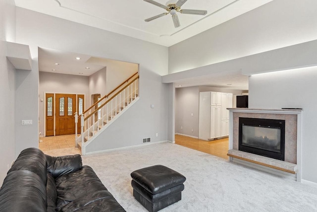 carpeted living room with ceiling fan and a high ceiling