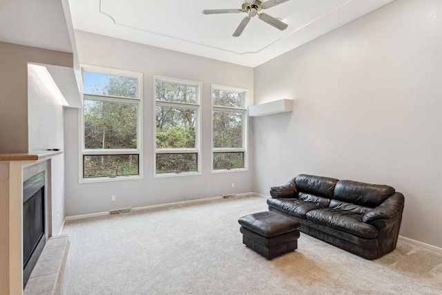 living room with light colored carpet, ceiling fan, and a fireplace