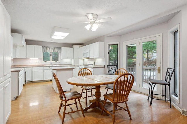 dining space with light wood-type flooring, a textured ceiling, and plenty of natural light