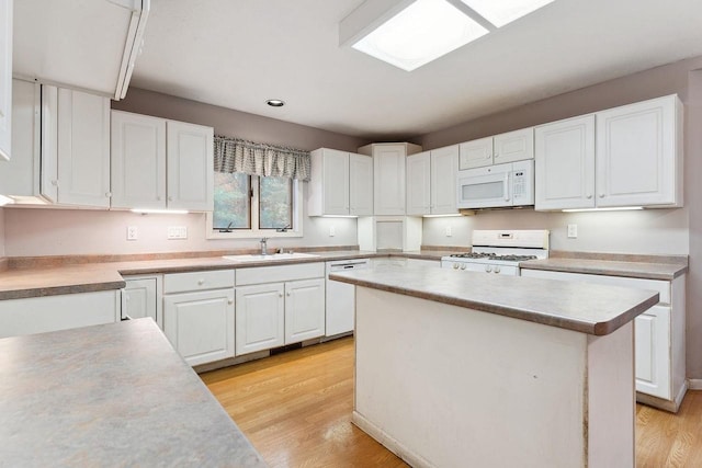 kitchen featuring white appliances, white cabinetry, sink, and light hardwood / wood-style flooring