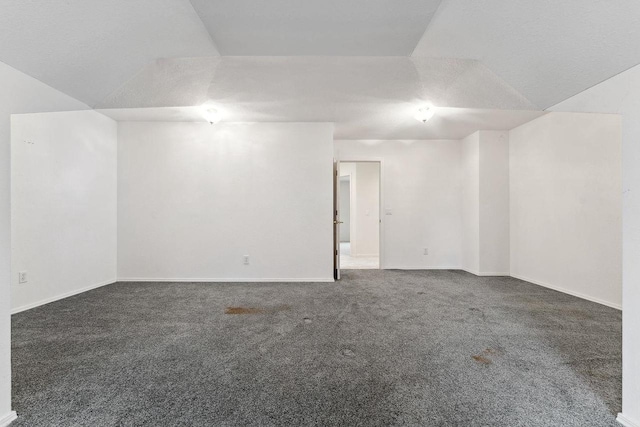 carpeted spare room featuring lofted ceiling and a textured ceiling