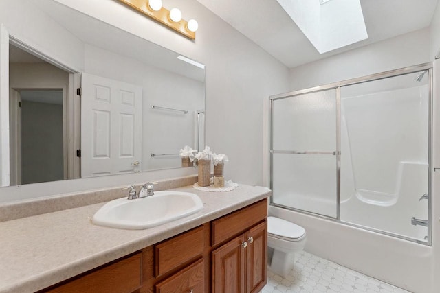 full bathroom featuring toilet, bath / shower combo with glass door, vanity, and a skylight