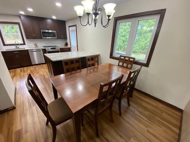 dining area featuring light wood-type flooring, a wealth of natural light, a notable chandelier, and sink