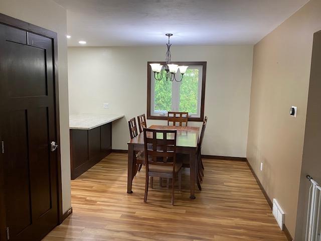 dining space featuring light hardwood / wood-style flooring and a notable chandelier