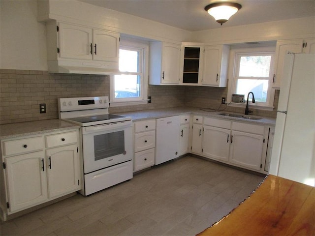 kitchen with white cabinetry, a wealth of natural light, sink, and white appliances