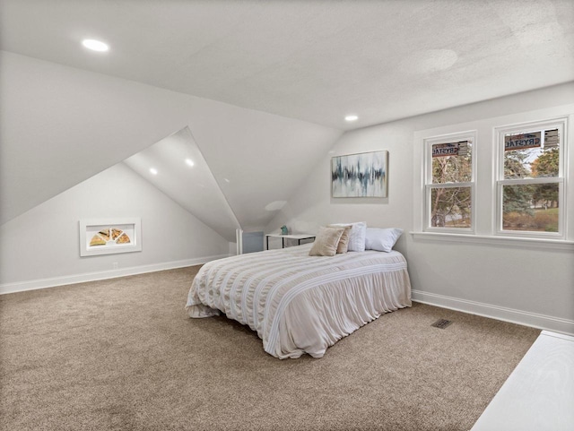 carpeted bedroom featuring a textured ceiling and lofted ceiling