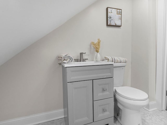 bathroom with tile patterned floors, vanity, vaulted ceiling, and toilet