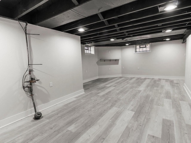 basement with light hardwood / wood-style floors and a wealth of natural light