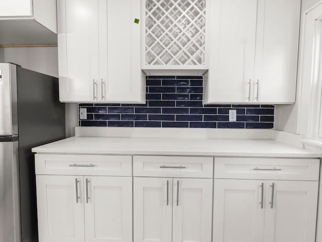 kitchen featuring white cabinets, stainless steel refrigerator, and tasteful backsplash