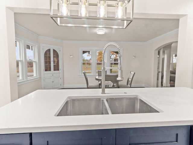 kitchen featuring blue cabinetry, crown molding, and sink