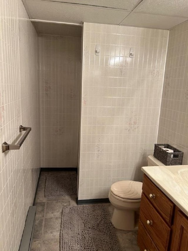 bathroom with vanity, toilet, and tile walls