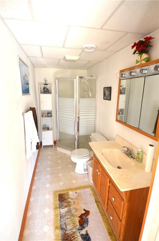 bathroom featuring vanity, a paneled ceiling, toilet, and a shower with shower door