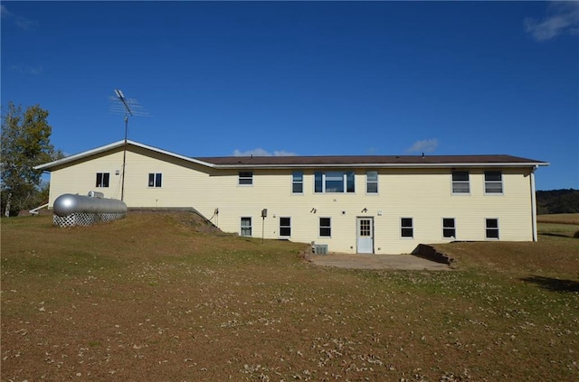 rear view of property featuring a lawn, a patio area, and cooling unit