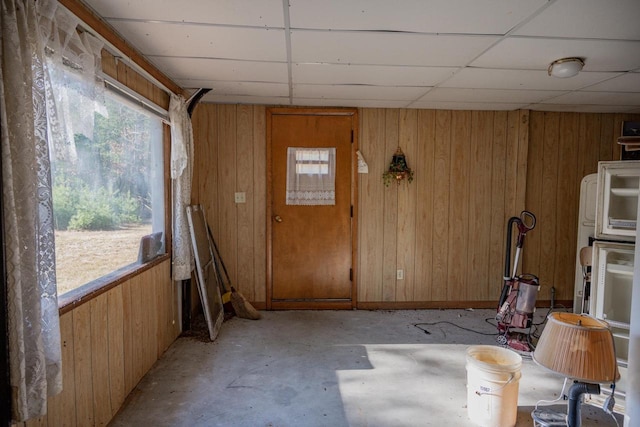 interior space featuring wooden walls and a drop ceiling