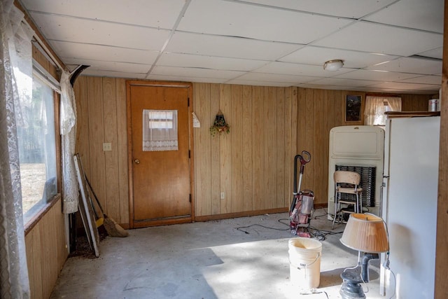 interior space with a drop ceiling and wooden walls