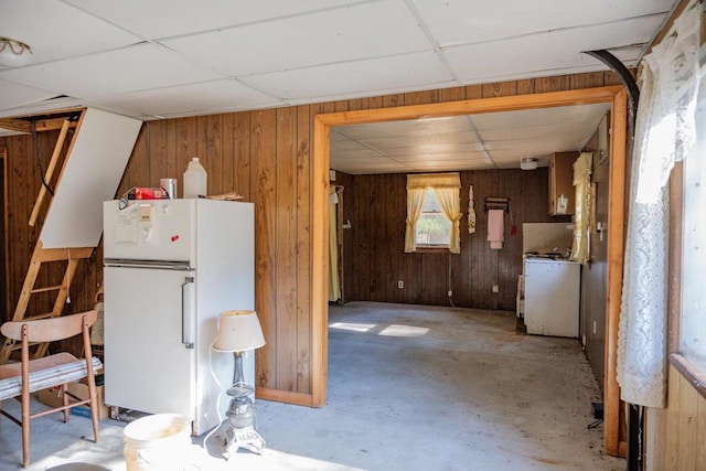 kitchen with a paneled ceiling, wood walls, and white fridge