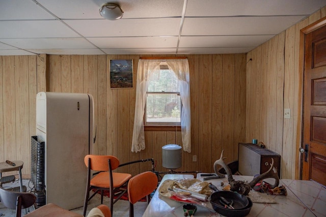 living area with a paneled ceiling and wooden walls