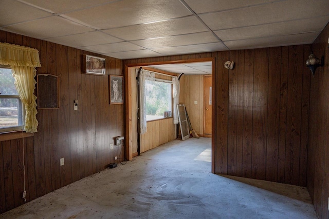 empty room featuring wooden walls and a paneled ceiling