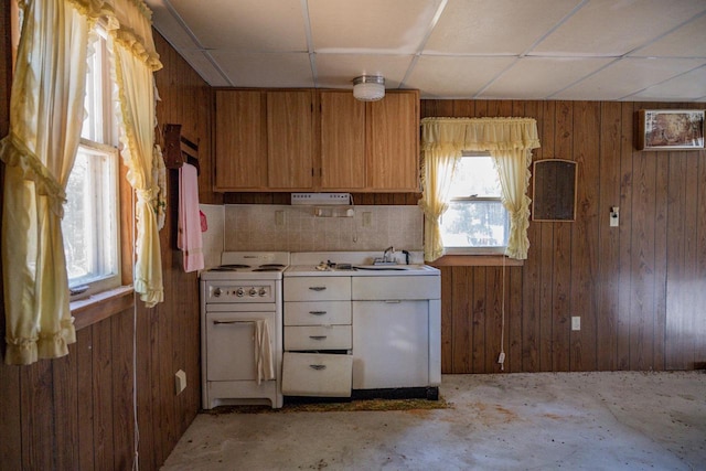 kitchen featuring wooden walls, sink, white stove, and a drop ceiling