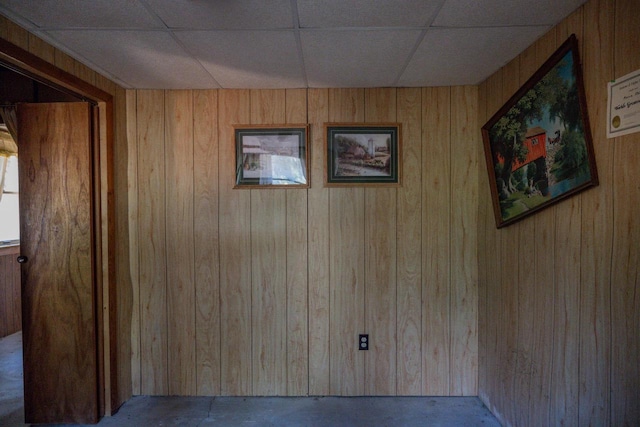 interior space with wood walls and a paneled ceiling