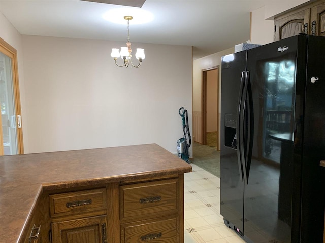 kitchen featuring black fridge, decorative light fixtures, and an inviting chandelier