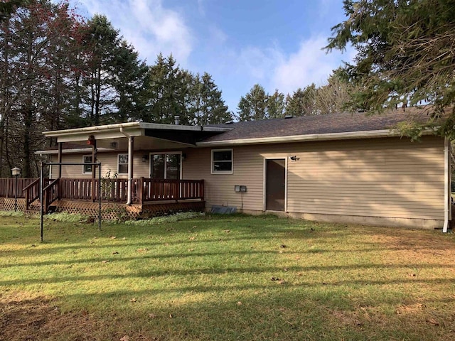 rear view of property with a wooden deck and a yard