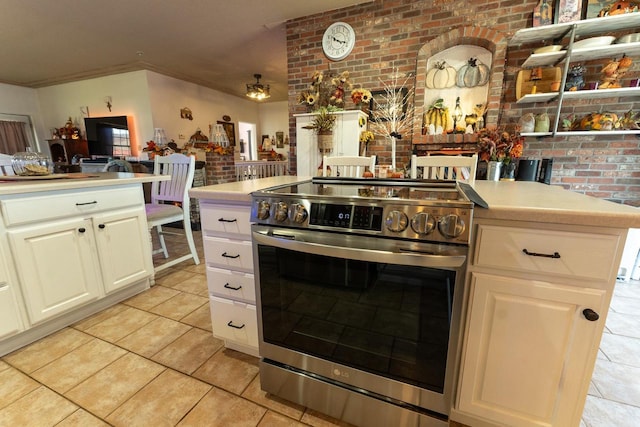 kitchen featuring white cabinetry, brick wall, double oven range, and light tile patterned flooring