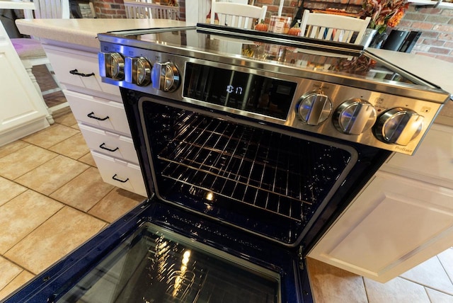 interior details with white cabinetry, light tile patterned floors, and range with two ovens