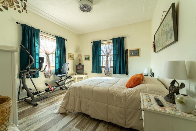 bedroom featuring a textured ceiling, light wood-type flooring, and multiple windows