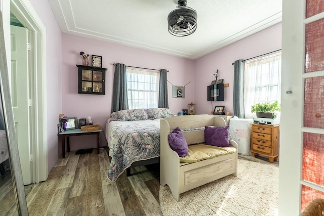 bedroom with a textured ceiling, wood-type flooring, and multiple windows