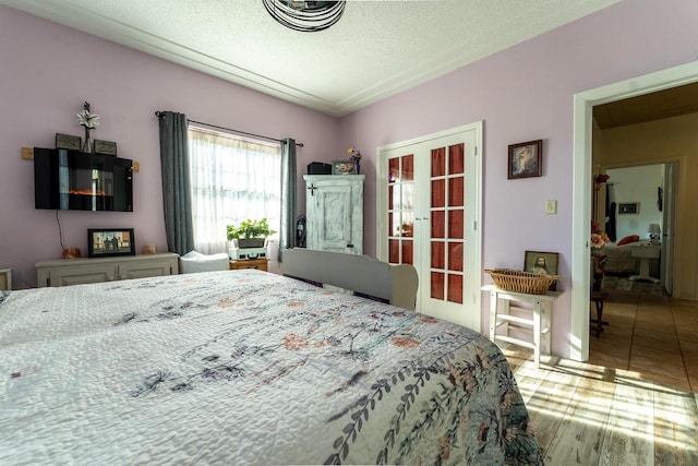 bedroom with a textured ceiling, french doors, and light tile patterned flooring