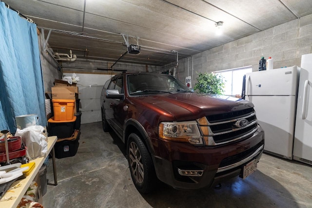 garage with a garage door opener and white refrigerator