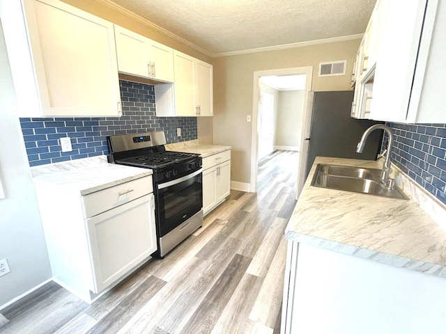 kitchen with white cabinets, stainless steel gas range, sink, and light wood-type flooring