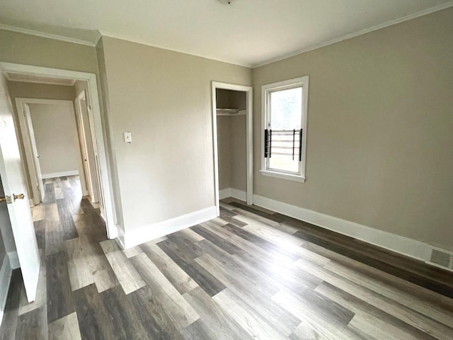 unfurnished bedroom with ornamental molding, dark wood-type flooring, and a closet