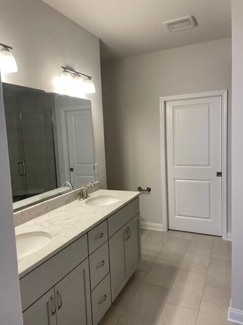 bathroom featuring tile patterned flooring, vanity, and a shower with door