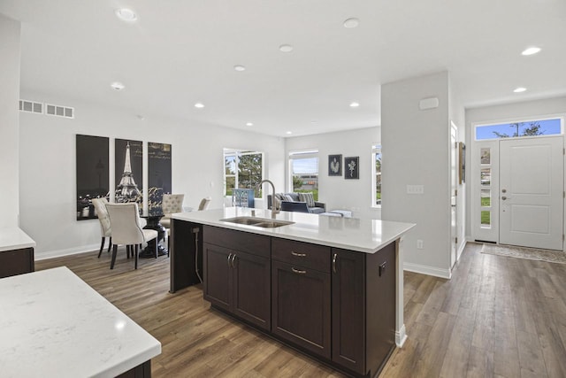 kitchen with hardwood / wood-style flooring, dark brown cabinetry, sink, and a kitchen island with sink