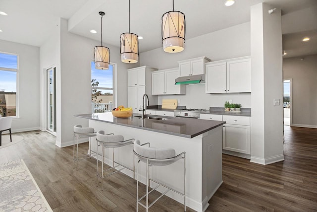 kitchen featuring white cabinets, sink, an island with sink, dark hardwood / wood-style floors, and decorative light fixtures