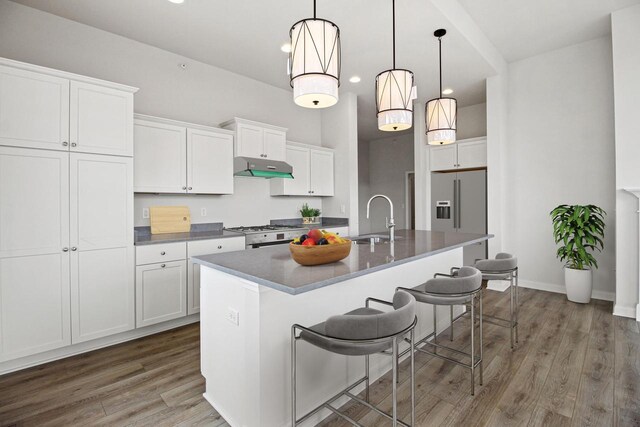 kitchen featuring a center island with sink, sink, decorative light fixtures, white cabinets, and dark hardwood / wood-style flooring